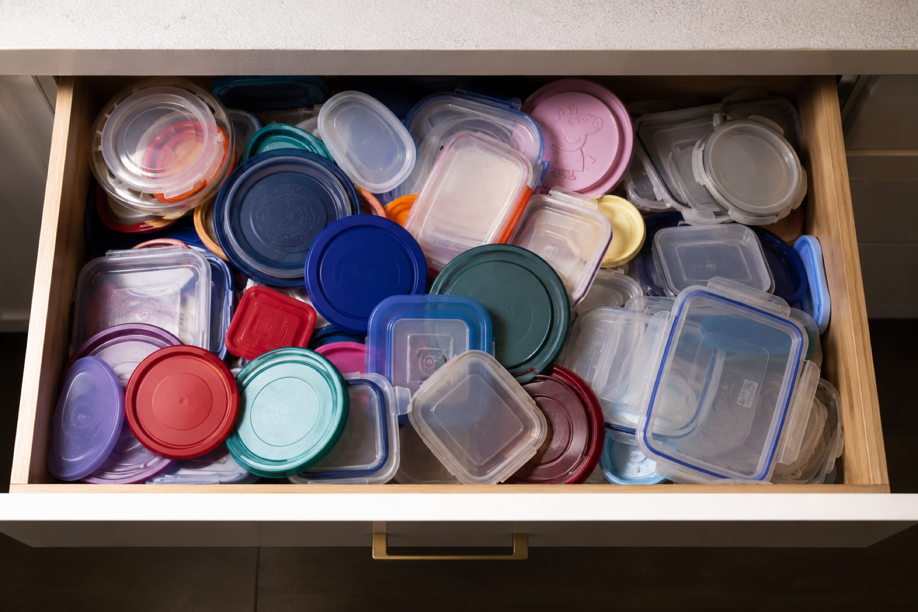 Overflowing cabinet filled with mismatched food containers